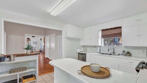 A modern kitchen with white cabinetry, a central island, and a view of the dining area.