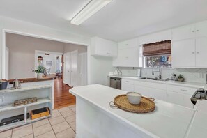 A modern kitchen with white cabinetry, a central island, and a view of the dining area.