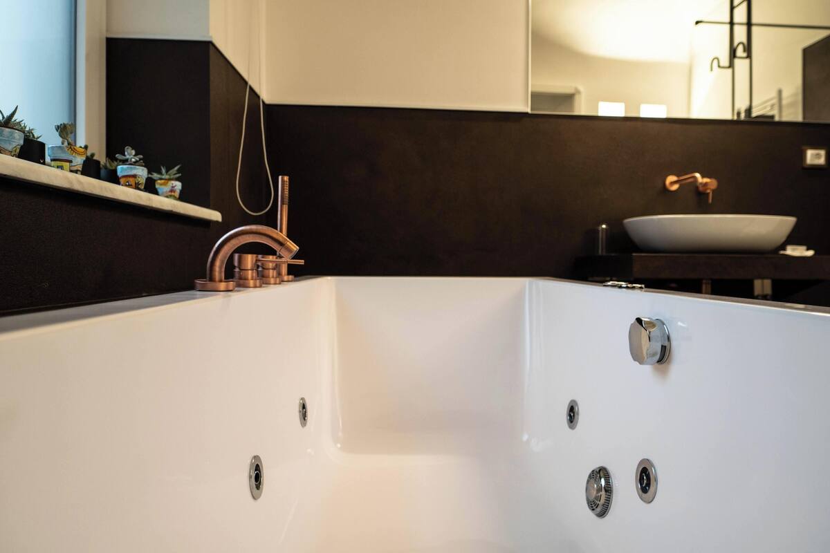 Une salle de bain moderne avec une grande baignoire blanche, un robinet en cuivre et un lavabo blanc.