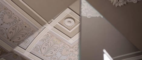 A ceiling with intricate floral and geometric patterns, a central medallion, and a decorative finial.