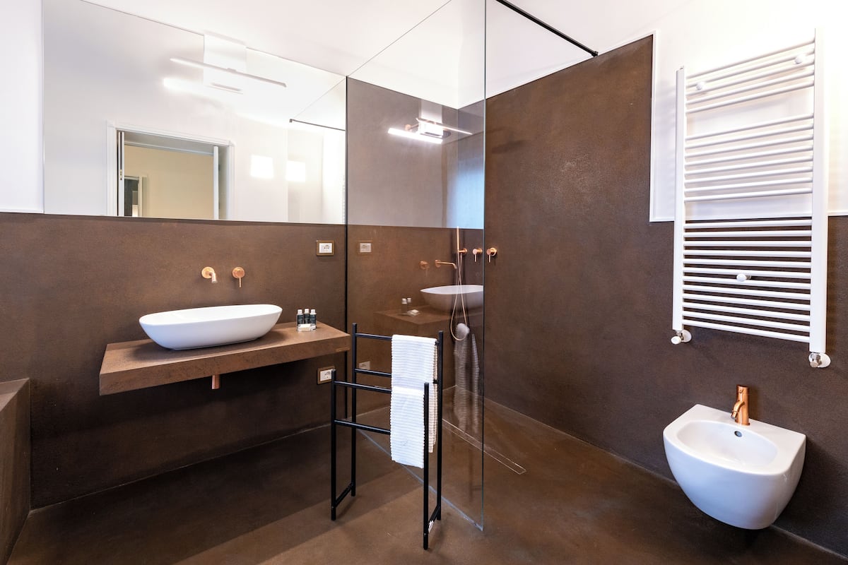 Une salle de bain moderne avec un grand miroir, un lavabo sur colonne, un bidet et un porte-serviettes.