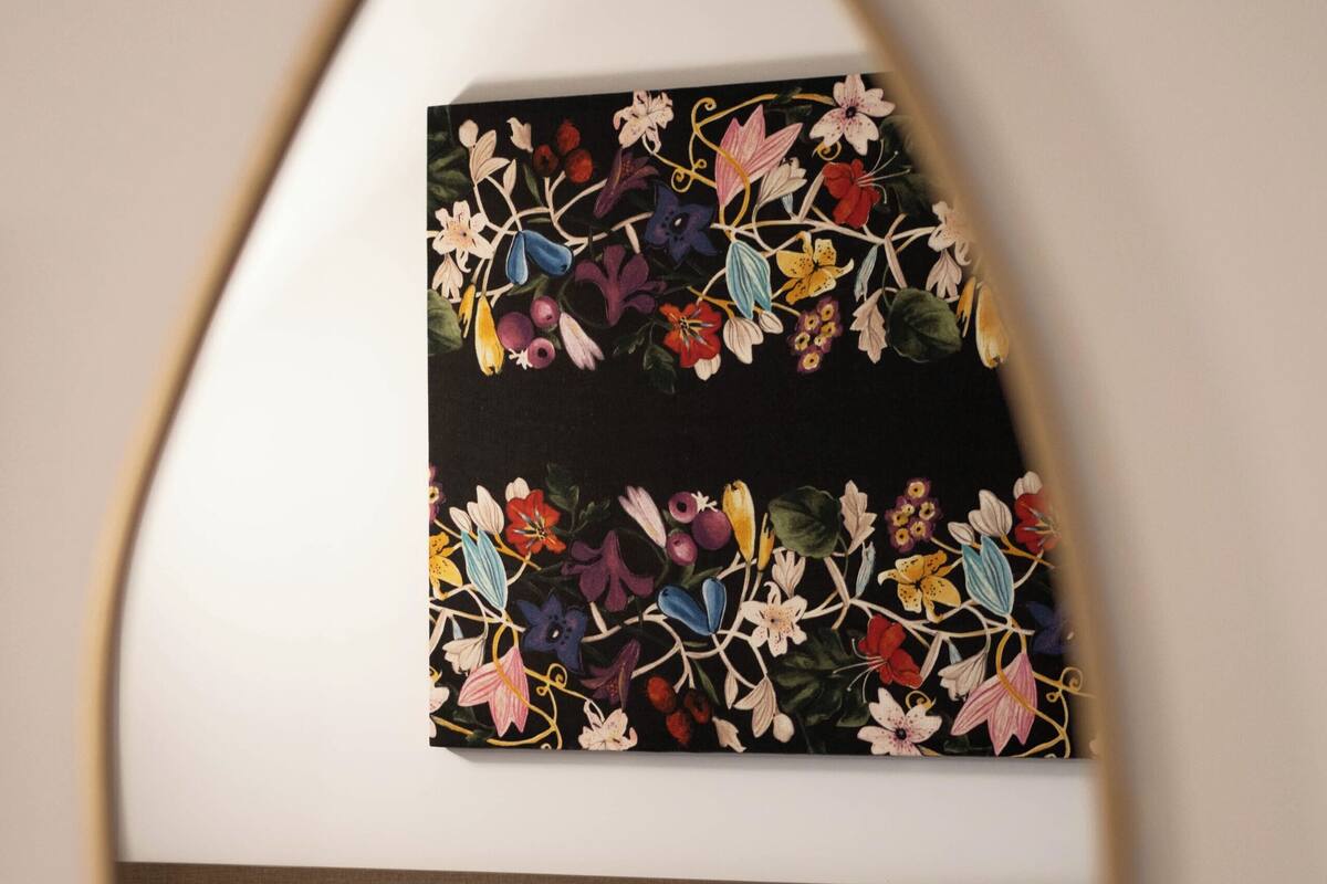 Une chambre d’hôtel avec un lit, une table de chevet, une lampe et un tableau représentant des fleurs accroché au mur.