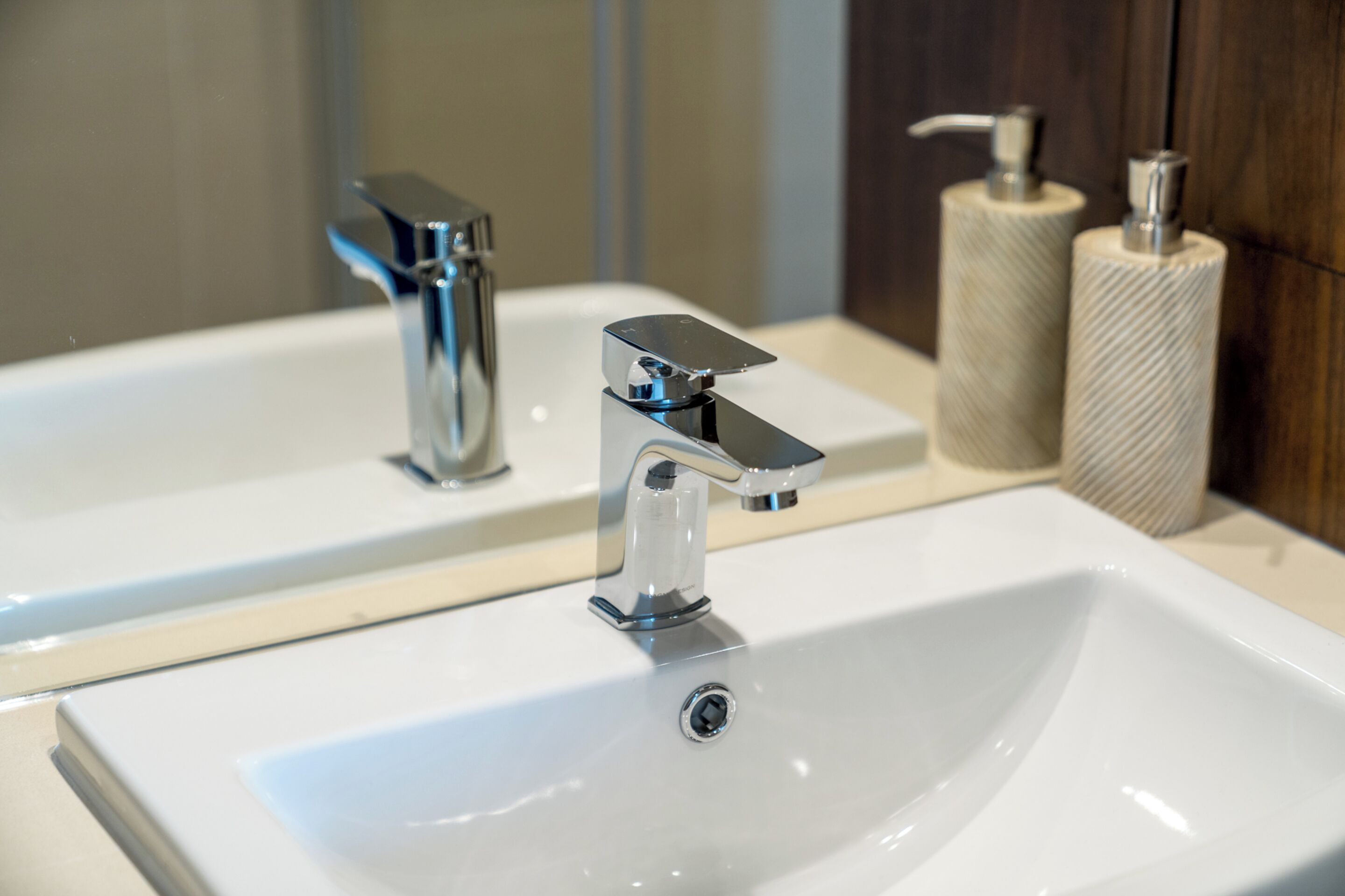 Une salle de bain avec deux lavabos, chacun doté d’un robinet chromé, et deux distributeurs de serviettes en papier.