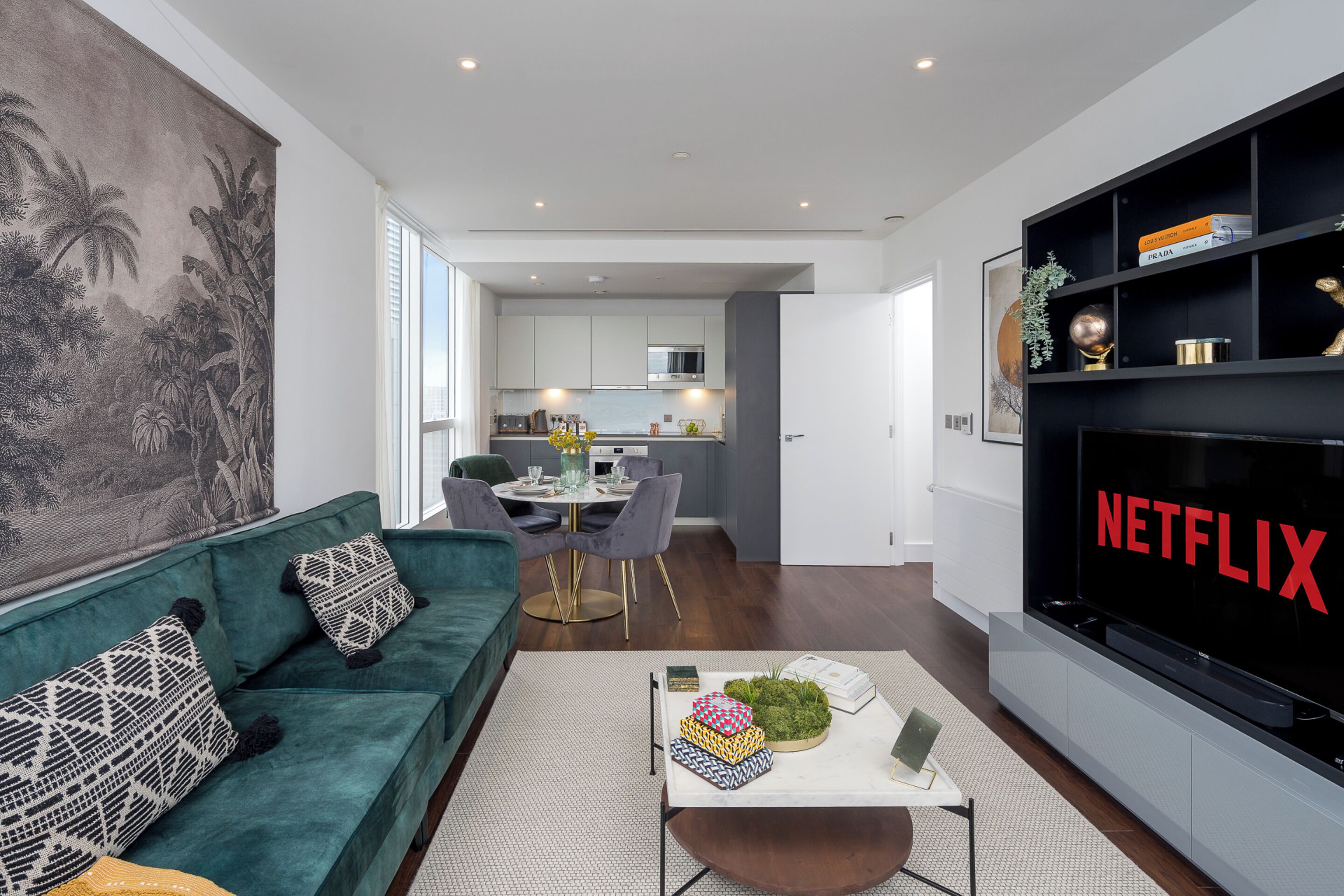 A modern living room with a green sofa, a coffee table, and a flat-screen TV displaying "NETFLIX".