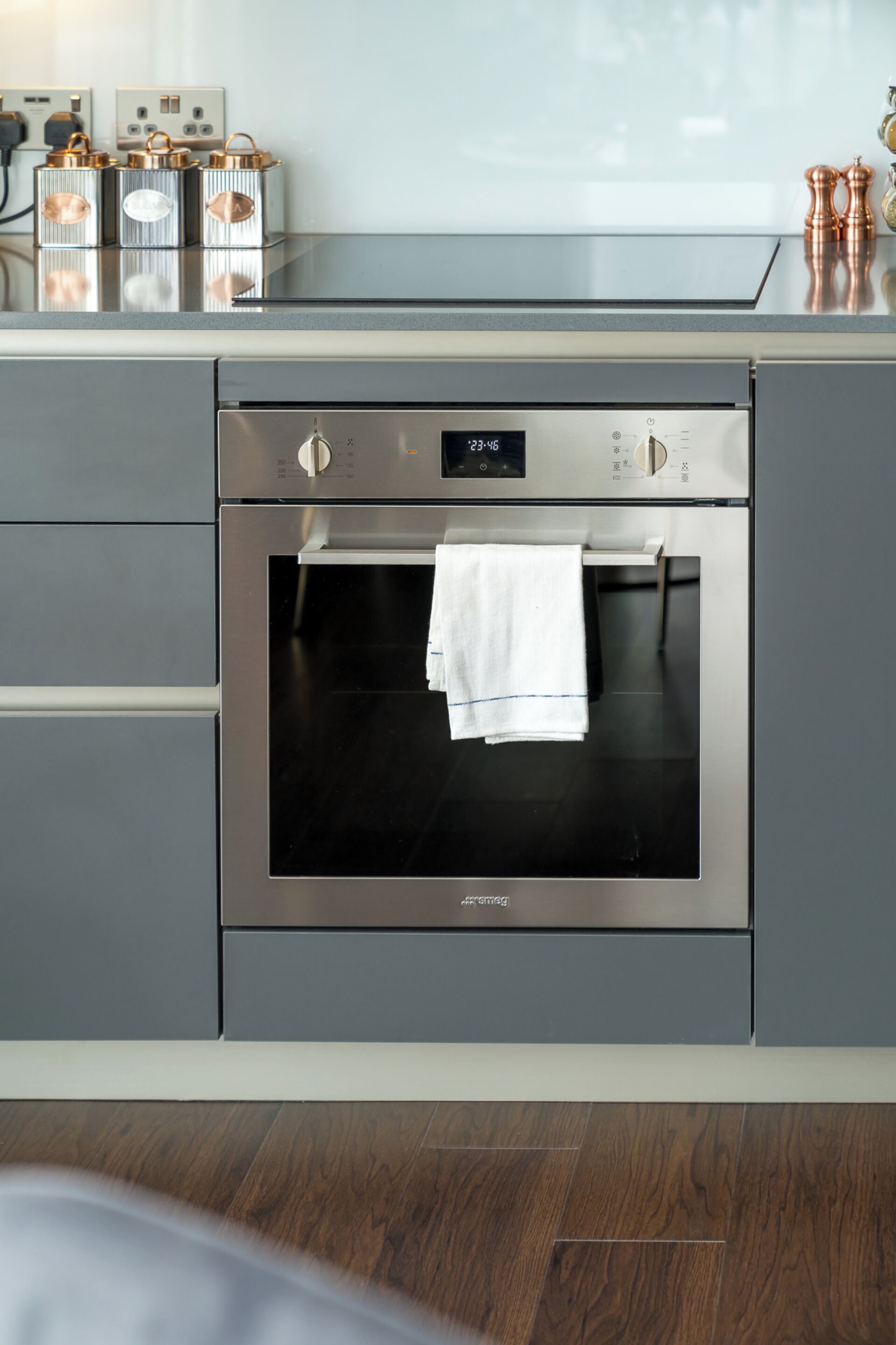 Eine moderne Küche mit einem Edelstahlbackofen, einer digitalen Uhr und einem Handtuch, das an der Backofentür hängt.