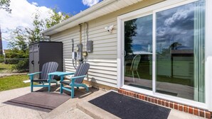 A house with a sliding glass door, a small outdoor seating area with two chairs and a table, and a covered outdoor storage unit. - Charming 3BR Home with Free Parking & Game Room (Panama City)