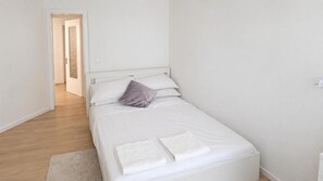 A single-bed room with a white headboard, a grey pillow, and two folded white towels on the bed. - Rapallo 2-bed Apartment, Sleeps 5 With Hot Tub (Rapallo)