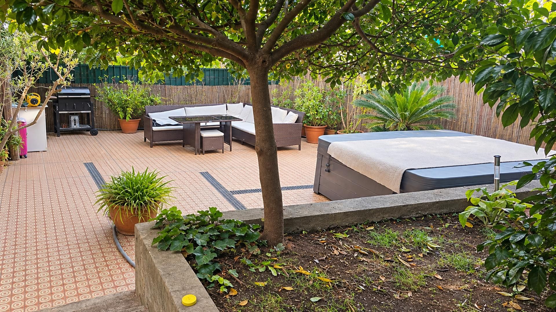 Un patio con una zona de estar, una parrilla y plantas en macetas.