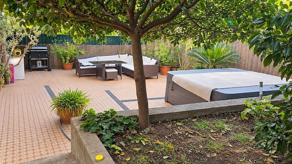 A patio area with a seating arrangement, a barbecue grill, and potted plants. - Rapallo 2-bed Apartment, Sleeps 5 With Hot Tub (Rapallo)