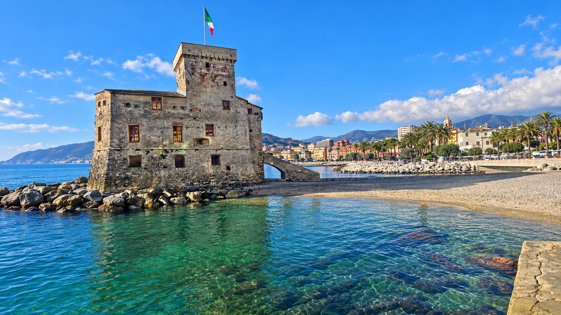 Um edifício de pedra com uma bandeira, mar azul cristalino e costa rochosa.
