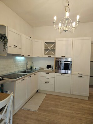 A kitchen with white cabinets, a stainless steel oven, a built-in sink, and a chandelier. - Rapallo 2-bed Apartment, Sleeps 5 With Hot Tub (Rapallo)
