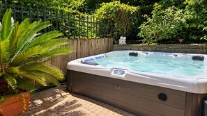 Ein Whirlpool in einem Garten mit Holzzaun und üppiger Bepflanzung.