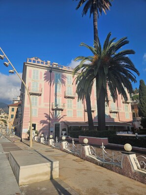 Um edifício rosa com varandas e uma palmeira na frente.