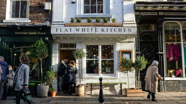 Um edifício com uma placa que diz 'FLAT WHITE KITCHEN', indicando um estabelecimento de refeições.