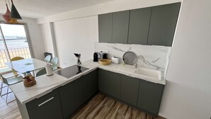 Une cuisine moderne dotée d’une grande fenêtre, de meubles de couleur sombre et d’un pare-feu en marbre.