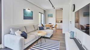 A modern living room with a sofa, a coffee table, and a dining area with chairs.