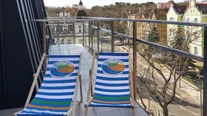 A balcony with two lounge chairs and a view of a town.