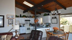 Un amplio salón con un sofá de cuero, una mesa de comedor de madera y una cocina al fondo.