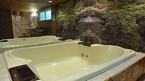 Un área de spa con una bañera grande, techo de madera y un mural con plantas.
