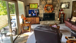 Una sala acogedora con chimenea de piedra, un televisor y un espacio de descanso confortable.