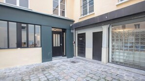A courtyard with a cobblestone floor, a black door, and a glass storefront.