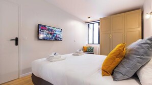 A hotel room with a bed, a TV mounted on the wall, a wardrobe, and a window.