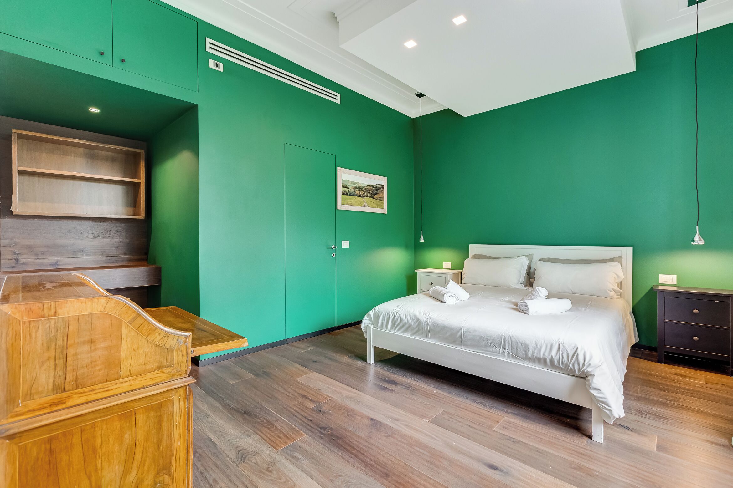 Un dormitorio con cama, escritorio de madera y paredes verdes.