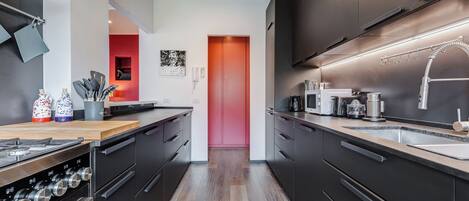 Een moderne keuken met donkere kastjes, roestvrijstalen apparatuur en een houten aanrecht.