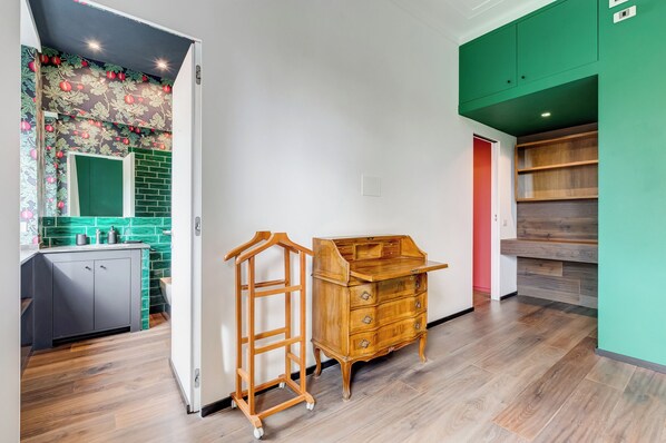 A modern kitchen with a wooden dresser, a hanging rack, and a green accent wall.