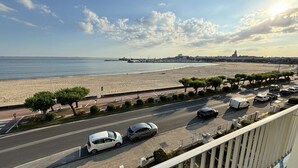 Eine Küstenstraße mit Strand und Stadtansicht im Hintergrund.