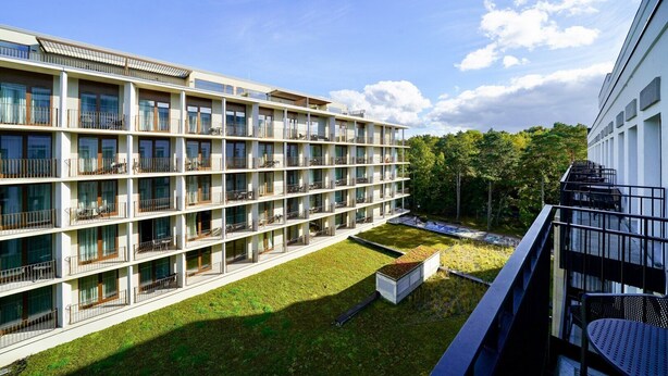 A multi-story hotel with balconies, a rooftop garden, and a clear view of the surrounding trees. - Fort by Baltic Home (Swinoujscie)