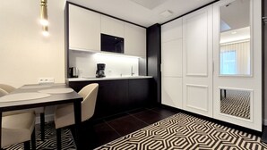 A modern kitchen with a dining area, featuring a black and white color scheme, a patterned rug, and a coffee machine. - Fort by Baltic Home (Swinoujscie)