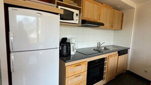 A compact kitchen with a white refrigerator, a microwave, a coffee maker, and wooden cabinets. - Ski-in/Ski-out Apt for 6 with Pool, Spa & Parking - Belle Plagne High (Belle Plagne)