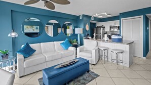 A modern living room with a white sofa, blue ottoman, and a ceiling fan. - Beach Retreat 2 Bedroom Ocean View, Pool & Beach (Tavernier)
