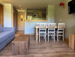 Cozy living space with a sofa, coffee table, dining area, and kitchenette.