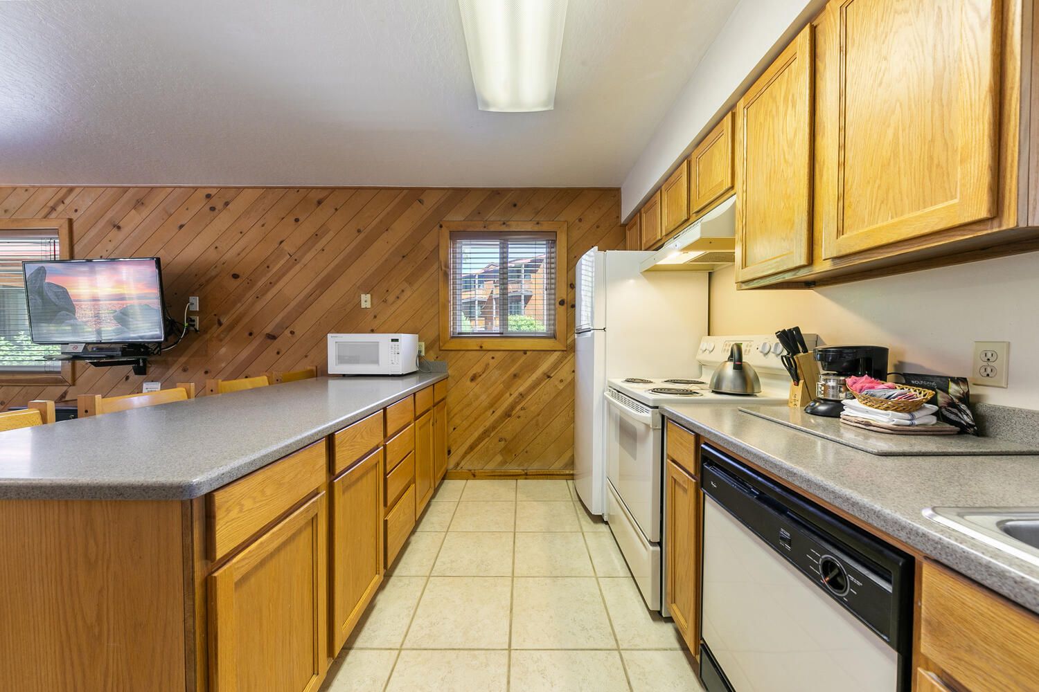 A kitchen with wooden cabinets, a microwave, a stove, and a dishwasher.