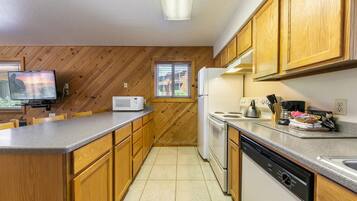 A kitchen with wooden cabinets, a microwave, a stove, and a dishwasher.