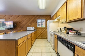 A kitchen with wooden cabinets, a microwave, a stove, and a dishwasher.
