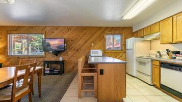 A compact kitchen with wooden cabinetry, a central island, a microwave, a stove, and a dishwasher.
