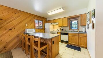A kitchen with wooden cabinets, a microwave, a stove, and a sink.