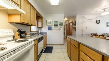 A kitchen with wooden cabinets, a stove, and a sink. There are framed pictures on the wall and a rug on the floor.