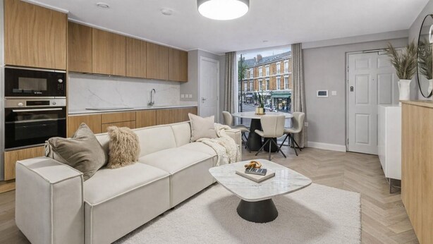 A modern living room with a sofa, coffee table, and a view of the street through a large window. - Modern 2B/2B Apt, Quiet Oxford St, A/C (London)