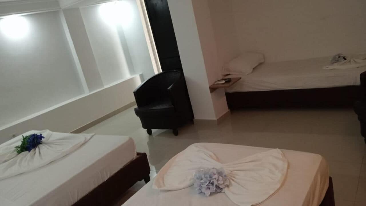 Una camera d'albergo con due letti, una sedia nera e un tavolino.