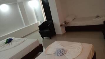 A hotel room with two beds, a black chair, and a small table.