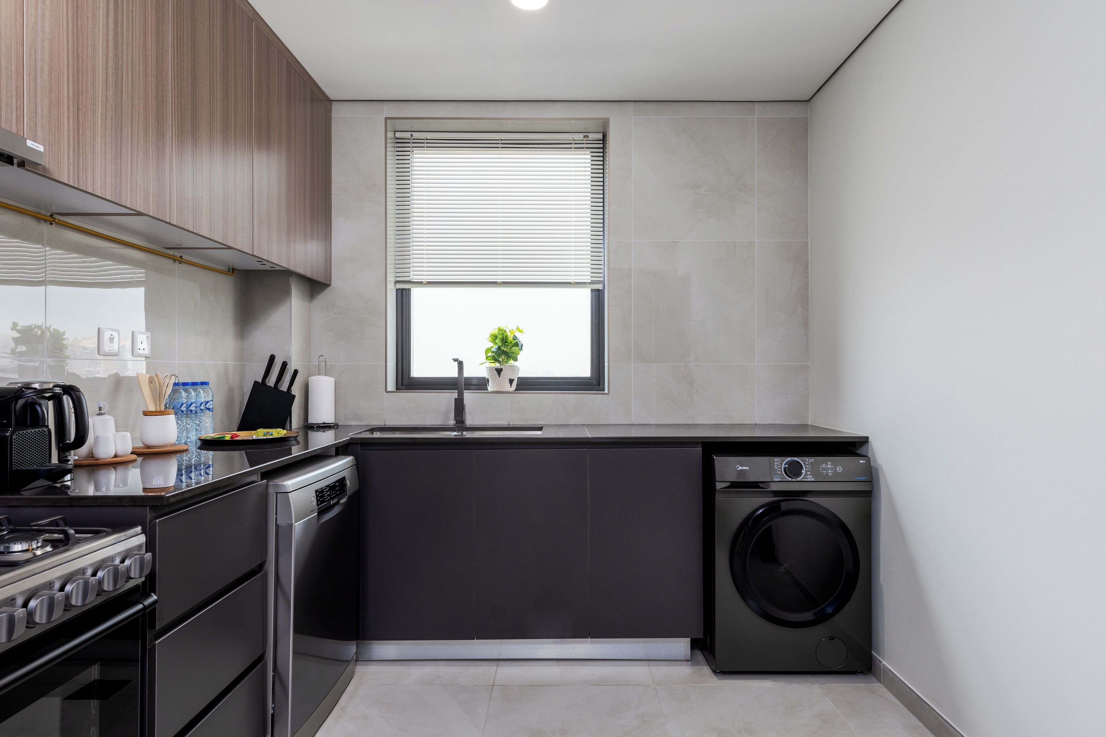 A compact kitchen with a built-in washer and dryer, a window with blinds, and a stove.