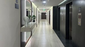 Ein moderner Hotelgang mit einer langen, geraden Halle, einem Empfangsbereich und einem Aufzug.