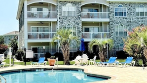 A multi-story hotel with a swimming pool, balconies, and outdoor seating. - Amazing 1BR condo on the ground floor (Myrtle Beach)