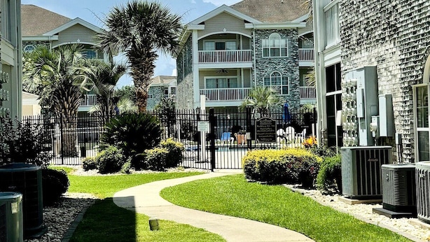 A residential building with a curved pathway, a small lawn, and a fence. - Amazing 1BR condo on the ground floor (Myrtle Beach)
