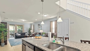 A modern kitchen with granite countertops, stainless steel sink, and overhead lighting. - Large retreat w/ pvt pool & cinema (Kissimmee)