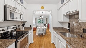 A modern kitchen with white cabinets, granite countertops, a stainless steel sink, and a built-in oven. - 148 Island House @ Forest Beach | Walk to Beach | Pool | Pet-Friendly | Tennis (Hilton Head Island)